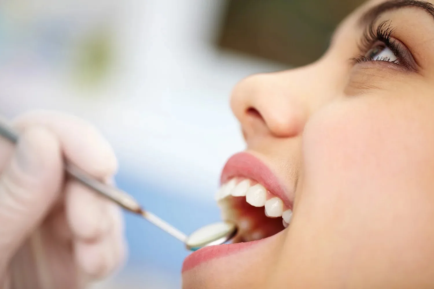 A dentist using a dental mirror to examine a patient's teeth.