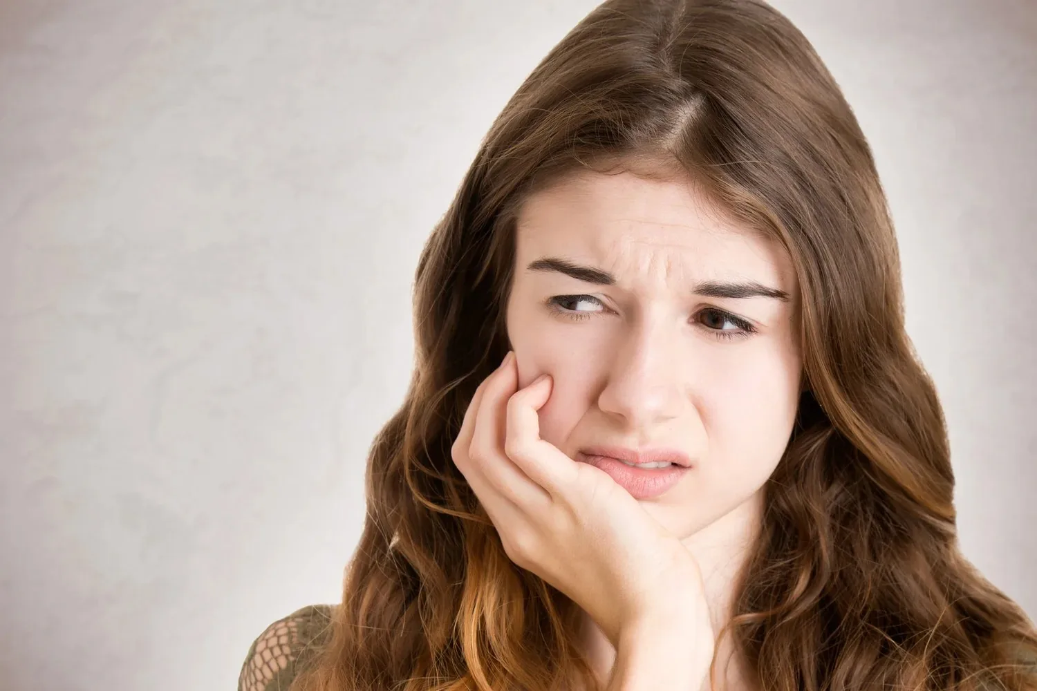 A person holding their jaw with an expression of pain and discomfort.